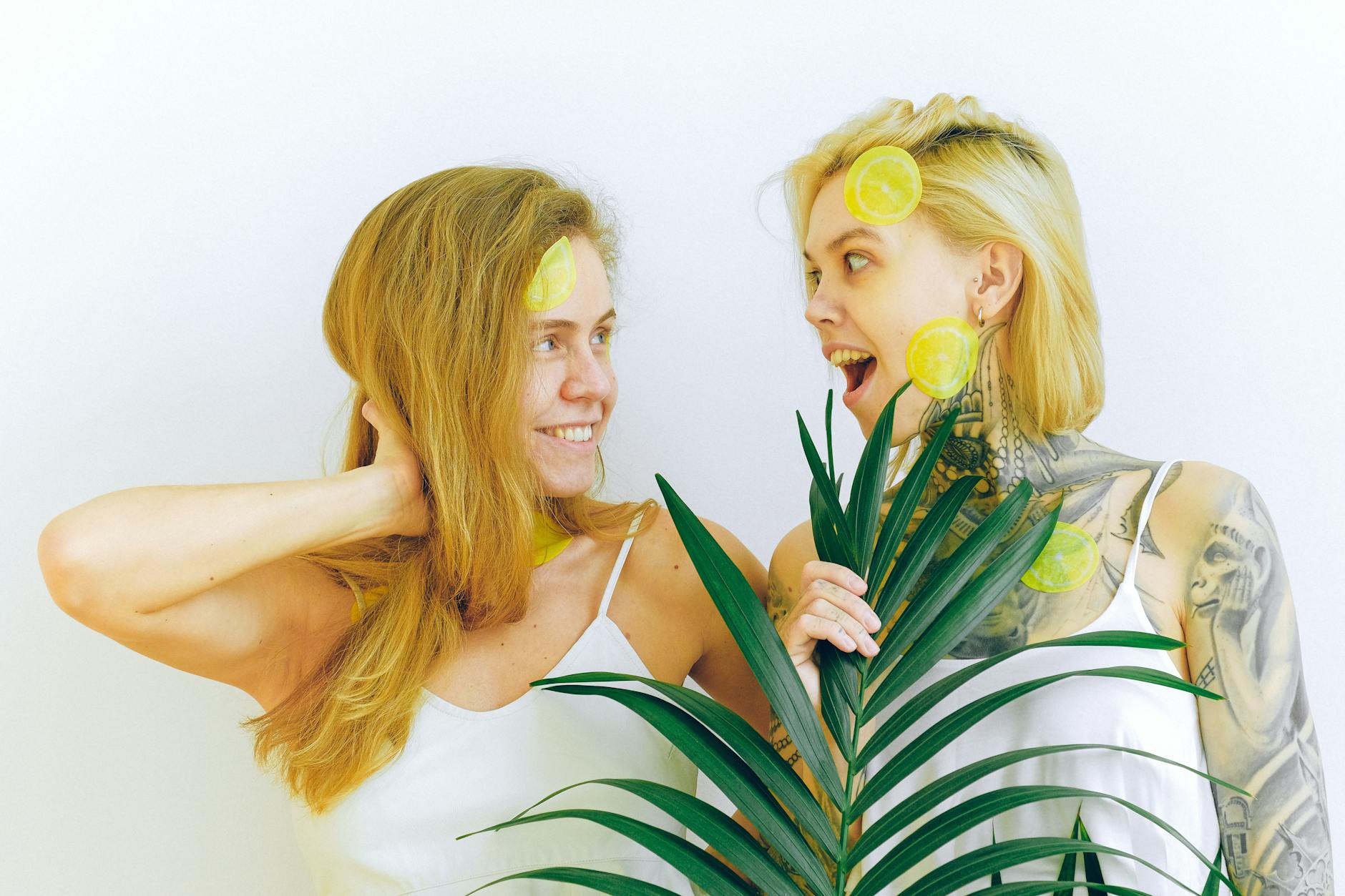 Two women smiling with lemons, expressing joy and comfort indoors