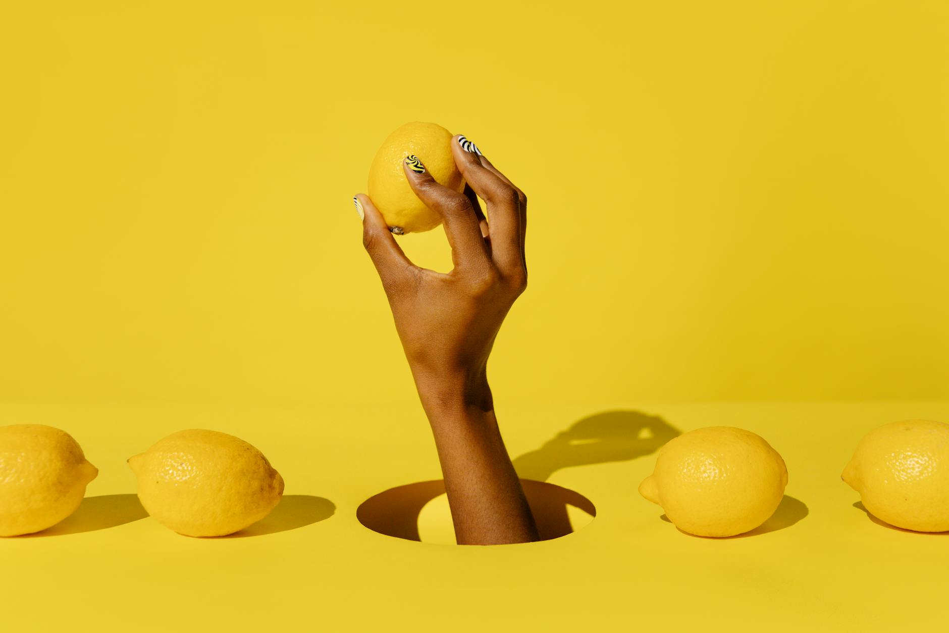 Hand holding a fresh lemon against a bright yellow background, symbolizing renewal and rediscovery