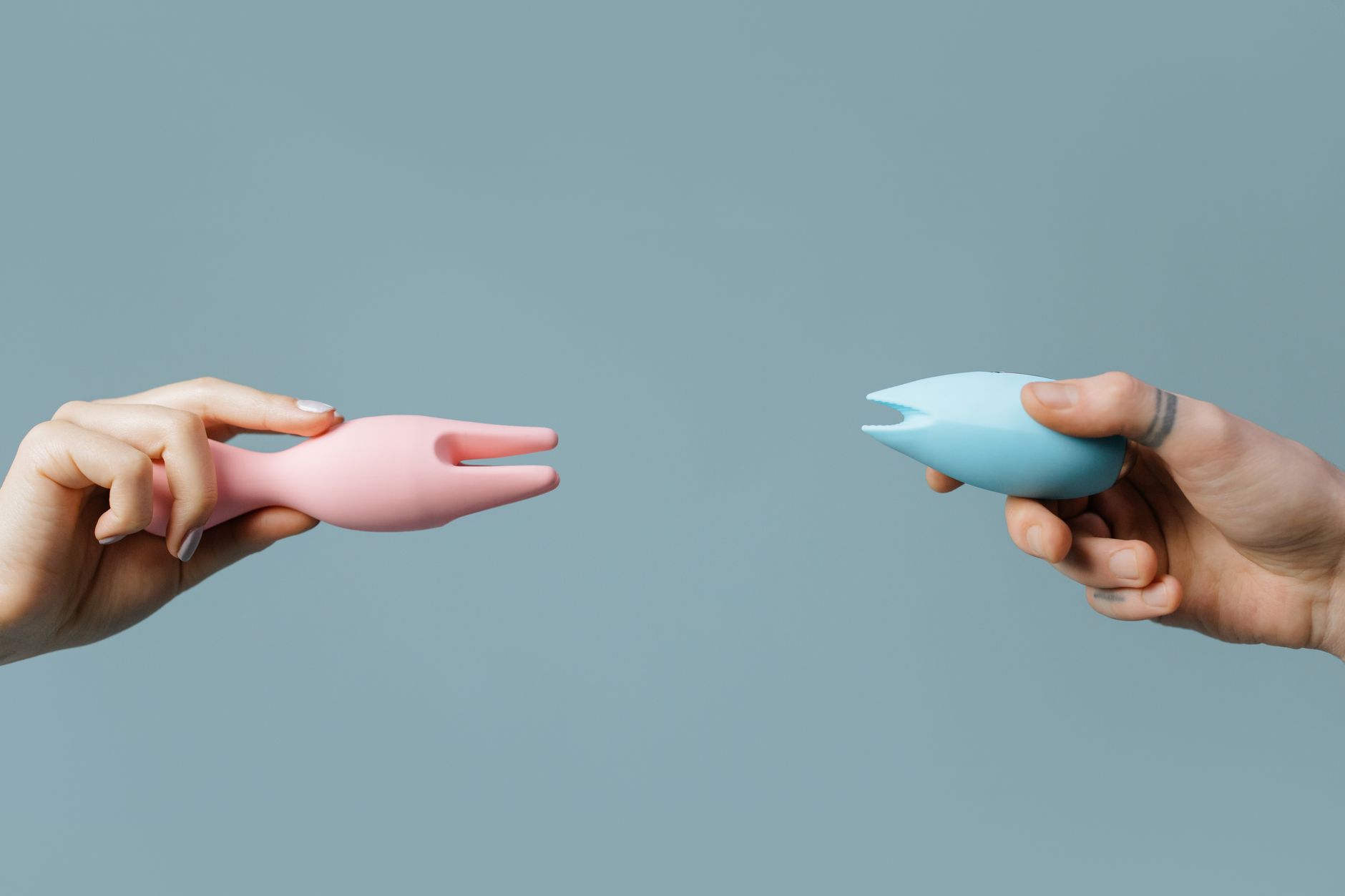 A close-up of hands holding a sleek blue vibrator against a soft background