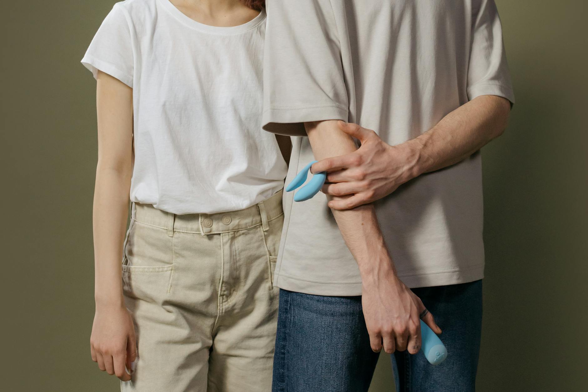 A couple standing together holding a blue vibrator, representing modern intimacy and pleasure exploration.